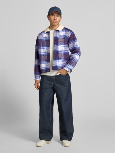 Männermodel trägt Oversized Hemdjacke mit Umlegekragen Modell 'TEDDY COLLAR BRUSHED' von Tommy Jeans, blau kariert, Ganzkörperansicht von vorne. Herren Hemdjacke von Tommy Jeans