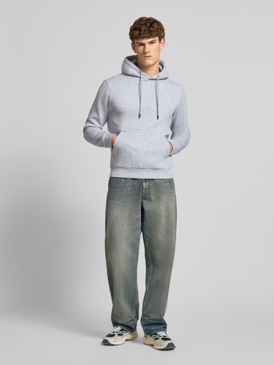 Männermodel trägt Hoodie mit Kapuze Modell 'BRADLEY' von Jack & Jones in Hellgrau, Baumwoll-Mix, Känguru-Tasche, Ganzkörperansicht von vorne.