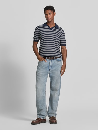 Męski model nosi Regular Fit Poloshirt mit V-Ausschnitt von Christian Berg Men z bawełny, kołnierzyk polo, dekolt w serek, krój regular fit, długość tyłu 68 cm, długość rękawów 27 cm, widok całej sylwetki z przodu.