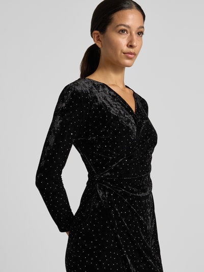 Vrouwenmodel draagt Samtkleid in Minilänge mit Stretch-Anteil van Apricot, zwart fluwelen stof met allover strass, tailleren fit, V-hals, lange mouwen, mini lengte, geplooide details, detailopname bovenlichaam.
