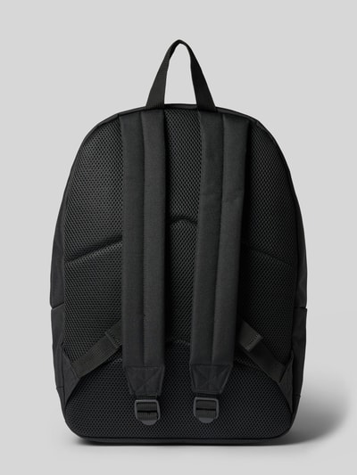 Produktfoto, Rucksack mit Label-Patch Modell 'Jake' von Carhartt Work In Progress, Schwarz, grobe Textur, gepolsterte Schulterriemen, Rückansicht, Hauptfach mit Zweiwege-Reißverschluss, kurzer Tragehenkel, Außenfach mit Reißverschluss, Mesh-Innenfach, Maße 40x45x14 cm, Schulterriemen 68 cm.
