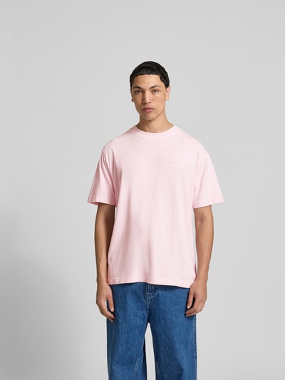 Männermodel trägt Regular Fit T-Shirt aus reiner Baumwolle von Closed in Rosa mit Rundhalsausschnitt, Used-Look, Label-Print, Ganzkörperansicht von vorne. Rückenlänge bei Größe M: 76 cm.