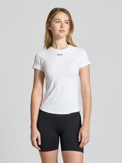 Modelka nosi T-Shirt mit Ziernähten od aim'n, kolor biały, krój slim fit, półprzezroczysty, okrągły dekolt, ozdobne szwy, długość pleców w rozmiarze S 55 cm, całkowity widok z przodu