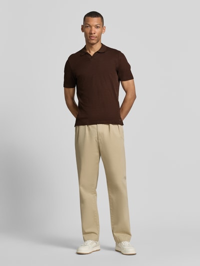 Männermodel trägt Modern Fit Poloshirt mit Polokragen und Label-Detail von MARKUP in Braun, kombiniert mit beiger Hose, Ganzkörperansicht von vorne. Herren Poloshirt aus reiner Baumwolle, Rückenlänge bei Größe M 70 cm.