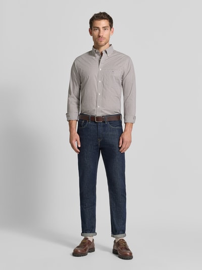 Männermodel trägt Regular Fit Freizeithemd aus reiner Baumwolle von GANT in Beige, kombiniert mit Jeans, Ganzkörperansicht von vorne.