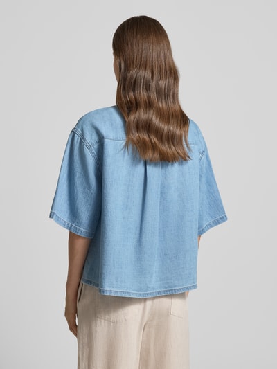 Vrouwenmodel draagt Relaxed Fit Jeansbluse uit zuivere katoen van s.Oliver RED LABEL in lichte denimkleur, twillstructuur, rugpas met Cacharel-plooi, korte mouw, rechte pasvorm, label patch, hemdkraag, V-hals, enkelrijige knoopsluiting, geheel achteraanzicht.