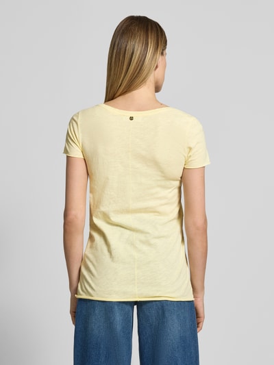 Kobiece model prezentuje damski t-shirt 'T-Shirt mit Rundhalsausschnitt und Rollsaum' od Rich & Royal, z bawełny, krój straight fit, okrągły dekolt, zrolowany brzeg, długość tyłu w rozmiarze S: 63 cm, jasny żółty kolor, faktura gładka, widok całego ciała z tyłu.
