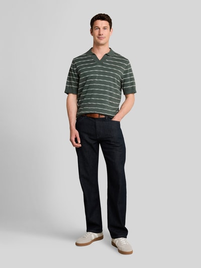 Männermodel trägt Regular Fit Poloshirt aus reiner Baumwolle von Tom Tailor in Grün mit weißen Streifen, Ganzkörperansicht von vorne. Herren Poloshirt