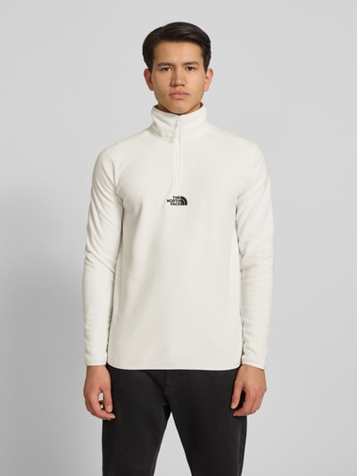 Männermodel trägt Fleecepullover mit Reißverschluss Modell 'GLACIER' von The North Face in Weiß, Regular-Fit, Stehkragen, Label-Stitching, Ganzkörperansicht von vorne. Rückenlänge bei Größe M 70 cm, Ärmellänge 67 cm.