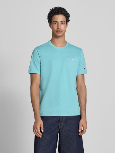 Männermodel trägt T-Shirt mit Logo-Stitchings Modell 'ICONS CONTRAST' von CHAMPION aus Baumwoll-Mix in Modern Fit, Rundhalsausschnitt, Rückenlänge bei Größe M 70 cm, Ganzkörperansicht von vorne.