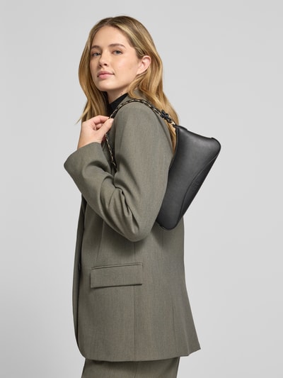 Vrouwenmodel draagt Clutch met Label-Prägung Modell 'Ilary' van HUGO in zwarte lederlook met schouderketting, detailopname zijaanzicht.