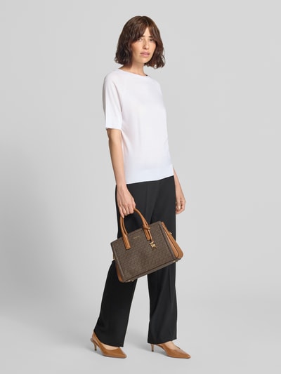 Frauenmodel trägt Handtasche mit Logo-Muster Modell 'LAILA' von MICHAEL Michael Kors, braun, Magnetverschluss, Tragehenkel, Ganzkörperansicht von vorne.