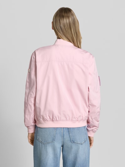 Männermodel trägt Bomberjacke mit Label-Patches Modell 'BROOKLYN NEO' von Frieda & Freddies, rosa, glatte Struktur, Ganzkörperansicht Rückansicht, prosty krój, krótki stójka, dwukierunkowy zamek, boczne kieszenie z patką i zatrzaskiem, ściągacze, długość tyłu w rozmiarze 36: 49 cm, szerokość ramion w rozmiarze 36: 42 cm, szerokość w biuście w rozmiarze 36: 55 cm, długość rękawa w rozmiarze 36: 63 cm