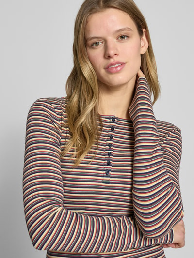 Frauenmodel trägt Slim Fit Longsleeve mit Knopfleiste von Review aus elastischem Baumwoll-Mix mit Rundhalsausschnitt, gestreiftes Muster, Nahaufnahme Oberkörper. Rückenlänge bei Größe S: 50 cm.