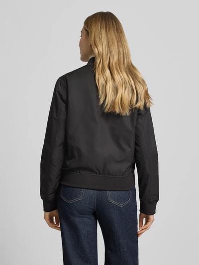 Frauenmodel trägt schwarze Regular Fit Jacke mit Stehkragen Modell 'Zaymi' von CARS JEANS, glatte Oberfläche, Eingrifftaschen, Reißverschluss, elastische Abschlüsse, Rückenlänge 61 cm, Schulterbreite 41 cm, Brustweite 39 cm, Ärmellänge 60 cm, Ganzkörperansicht Rückansicht.