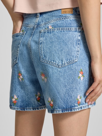 Frauenmodel trägt Regular Fit Jeansshorts aus reiner Baumwolle Modell 'SKY' von Pieces, Denim-Optik, Stickerei, Nieten, 5-Pocket-Design, Ganzkörperansicht Rückansicht.