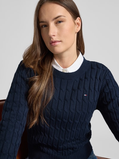 Frauenmodel trägt Slim Fit Strickpullover aus reiner Baumwolle von Tommy Hilfiger, navy, unifarben, gestreift, Logo, Nahaufnahme Oberkörper.