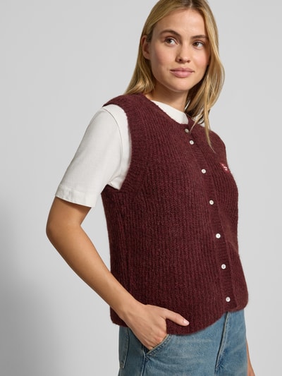 Modelka kobieca ma na sobie Regular Fit Weste mit Alpaka-Woll-Anteil od American Vintage, elastyczna mieszanka materiałów, imitacja dzianiny, detal z logo, listwa guzikowa, długość tyłu w rozmiarze S: 53 cm, widok całej sylwetki z przodu.