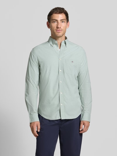 Männermodel trägt Regular Fit Freizeithemd aus reiner Baumwolle von GANT in Hellgrün mit feinem Karomuster, Ganzkörperansicht von vorne.
