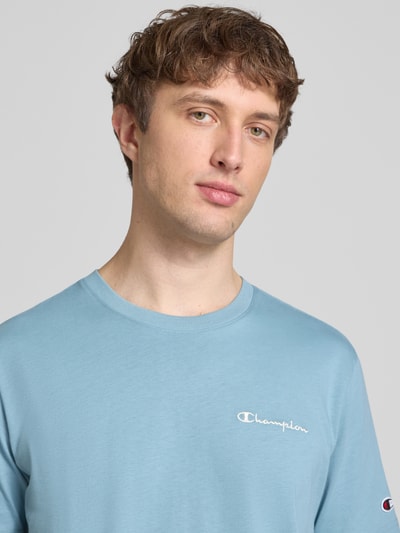 Mężczyznamodel nosi T-Shirt mit Label-Stitchings und Rundhalsausschnitt von CHAMPION, czysty bawełna, krój regular fit, jasnoniebieski, detal haftu, długość tyłu w rozmiarze M: 69 cm, zbliżenie górnej części ciała