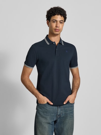 Männermodel trägt Slim Fit Poloshirt mit Logo-Stitching Modell 'Dunda' von G-Star Raw, Baumwoll-Mix, Ganzkörperansicht von vorne.