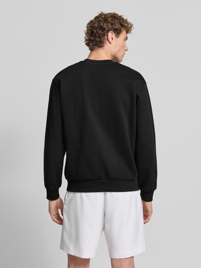 Männermodel trägt Regular Fit Sweatshirt aus Baumwoll-Mix von Lacoste in Schwarz, weiße Shorts, Ganzkörperansicht Rückansicht. Herren Sweatshirt