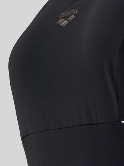 Frauenmodel trägt Slim Fit Badeanzug mit Shaping-Effekt von Arena, elastischer Stoff, schwarzer Farbton, Logo-Print, Nahaufnahme Oberkörper.