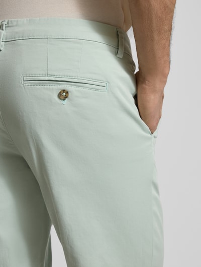 Männermodel trägt 'Slim Fit Chino aus Baumwoll-Mix' van SELECTED HOMME in effen kleuren met riemlussen en achterzak, detailopname rug. Context: heren chino, look: effen, pasvorm: slim fit, mid rise, sluiting: knoop en verdekte ritssluiting, materiaal: mix van biologisch katoen.