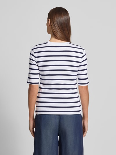 Frauenmodel trägt Basic T-Shirt Ringel O-Neck von Christian Berg Woman in Weiß mit navyfarbenen Streifen, körpernaher Schnitt, halbärmelig, Baumwoll-Elasthan-Mix, Rückenlänge 56 cm, Ganzkörperansicht Rückansicht.