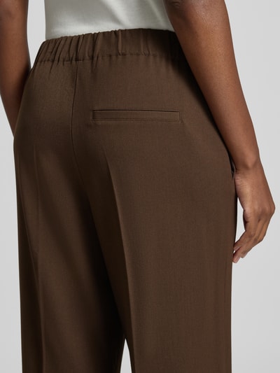 Frauenmodel trägt Regular Fit Weite Hose mit Viskose-Anteil Modell 'EMMA-TARA' von Selected in Braun mit glatter Textur, Nahaufnahme Rückansicht, Damen Weite Hose von Selected.