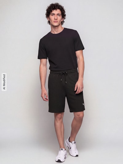 Männermodel trägt Relaxed Fit Sweatshorts aus Baumwoll-Mix 'ESS ELEVATED' von PUMA, neutrale Farben, glatte Textur, Herren Sweatshorts von PUMA Performance, Ganzkörperansicht von vorne, KI-modifiziertes Bild.