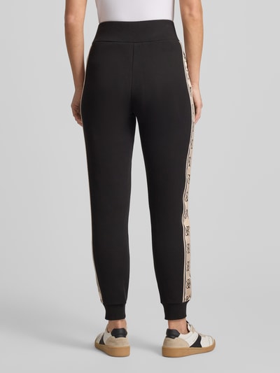 Frauenmodel trägt schwarze Sweatpants mit elastischem Bund Modell 'BRITNEY' von Guess Activewear, Baumwoll-Mix, lockerer Schnitt, Ganzkörperansicht Rückansicht.