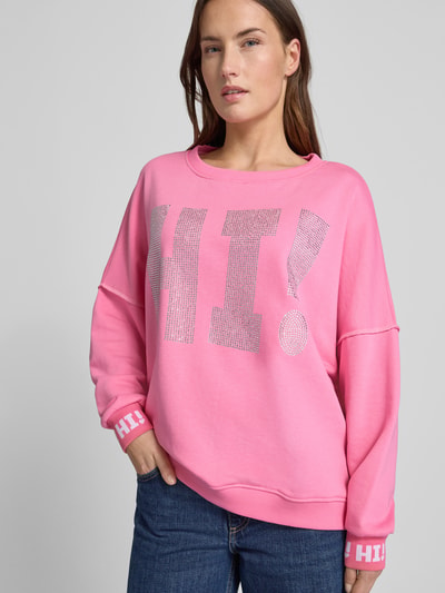 Modelka kobieca nosi różowy Sweatshirt mit Label-Detail od miss goodlife z bawełny, szeroki krój, ściągacze, napis HI!, zbliżenie górnej części.