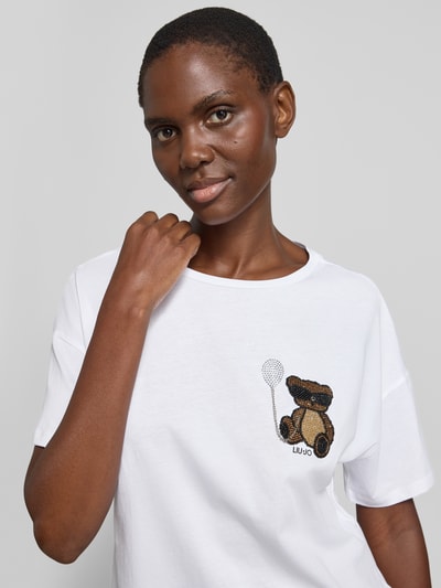 Frauenmodel trägt Regular Fit T-Shirt mit Ziersteinbesatz von Liu Jo White, Damen T-Shirt aus Reine Baumwolle, Logo-Print, Rundhalsausschnitt, weiße Farbe, glatte Textur, Ganzkörperansicht von vorne.