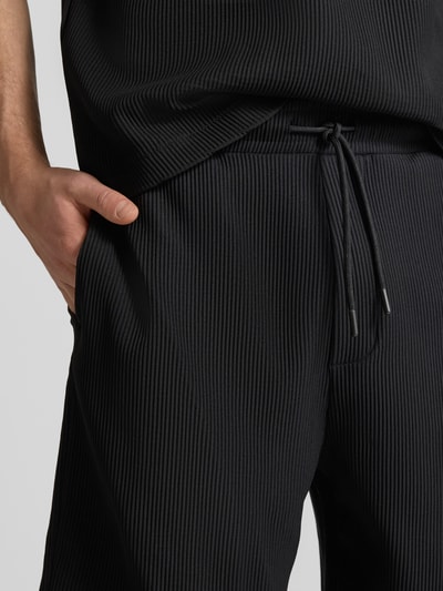 Männermodel trägt Shorts in Plissee-Optik mit elastischem Bund von REVIEW, schwarzer Material-Mix mit Stretch-Anteil, Nahaufnahme Oberkörper