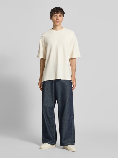 Männermodel trägt T-Shirt mit Strukturmuster und Rundhalsausschnitt Modell 'PETER' von Redefined Rebel, Relaxed Fit, helles Beige, Baumwoll-Mix, kombiniert mit weiter Jeans, Ganzkörperansicht von vorne.