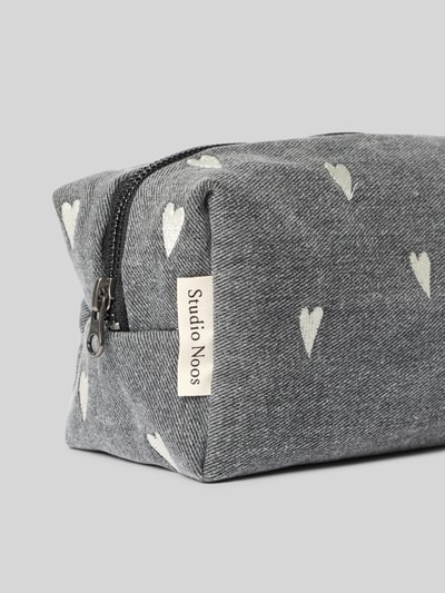 Produktfoto, Fanny Pack aus reiner Baumwolle mit Logo-Patch von Studio Noos, grauer Stoff, weiße Herzstickereien, Reißverschluss, Nahaufnahme Ecke, dezente Struktur, Allover-Motiv-Stitching, Maße 24 x 11 x 9 cm, Damen Accessoire.