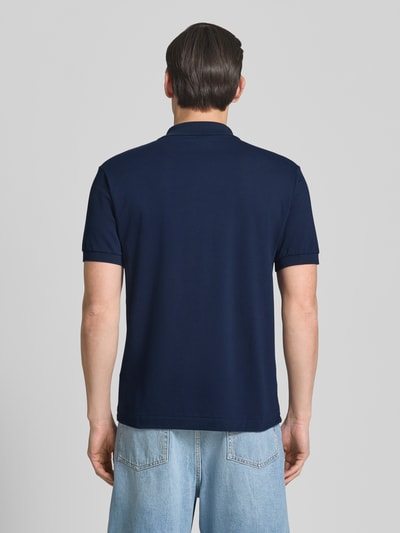 Männermodel trägt Regular Fit Poloshirt aus Baumwoll-Mix von Lacoste in Dunkelblau, unifarben, Logo-Detail, Ganzkörperansicht Rückansicht.