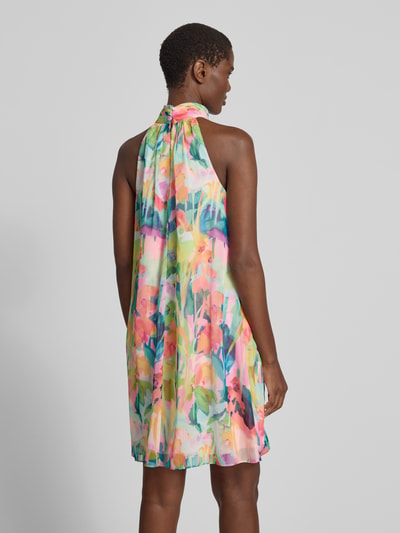 Frauenmodel trägt Cocktailkleid mit Stehkragen und Volants von Adrianna Papell in A-Linie, Allover-Look mit bunten Farben, Minilänge, Ganzkörperansicht Rückansicht.