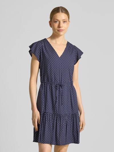 Vrouwenmodel draagt Minikleid uit zuiver viscose met V-hals van GAP, getailleerde pasvorm, tunnelkoord bij de taille, jurk met korte mouwen, donkerblauwe stof met witte stippen, borstwijdte 85 cm, mouwlengte 11 cm, vooraanzicht bovenlichaam.
