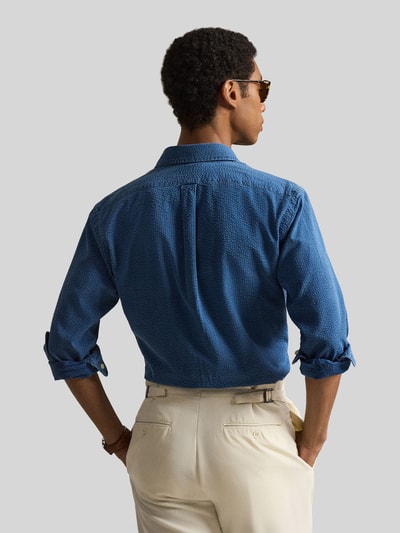 Männermodel trägt Regular Fit Freizeithemd aus reiner Baumwolle von Polo Ralph Lauren in Blau, Strukturmuster, Struktur-Optik, Twill, Langarm, Button-Down-Kragen, Logo-Stitching, Sportmanschette, Ganzkörperansicht Rückansicht.