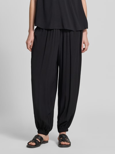 Frauenmodel trägt Relaxed Fit Jogginghose aus reiner Viskose Modell 'Radia' von Soyaconcept, schwarze Farbe, elastischer Bund, elastische Beinabschlüsse, Nahaufnahme Unterkörper, Vorderansicht.