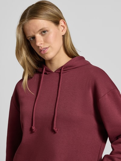 Frauenmodel trägt Regular Fit Hoodie aus Baumwoll-Mix Modell 'CHILLI' von PIECES in Dunkelrot, glatte Textur, Nahaufnahme Oberkörper.