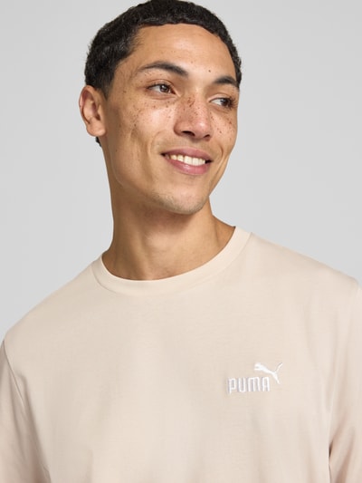 Männermodel trägt Regular Fit T-Shirt mit Logo-Stitching von PUMA PERFORMANCE in Beige, Rundhalsausschnitt, Nahaufnahme Oberkörper.