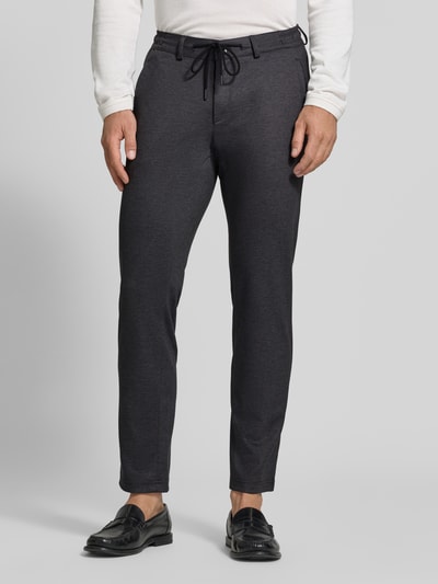 Männermodel trägt dunkelgraue Tapered Fit Jogpants mit Viskose-Anteil Modell 'Phil' von Brax, Herren Weite Hose, Ganzkörperansicht von vorne.