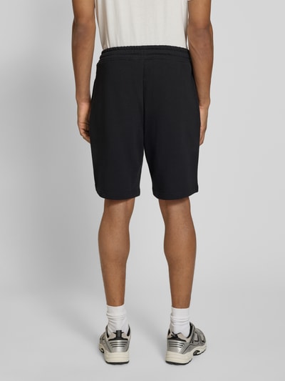 Männermodel trägt Regular Fit Sweatshorts aus reiner Baumwolle Modell 'DAYONO' von HUGO, unifarben, Sweatmaterial, Ganzkörperansicht Rückansicht.