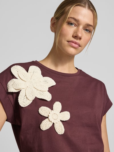 Vrouwenmodel draagt T-Shirt met Applikationen und Rundhalsausschnitt van Christian Berg Woman in bordeauxrood katoen, regular fit, bloemenapplicaties, ronde hals, ruglengte maat S 60 cm, close-up bovenlichaam.
