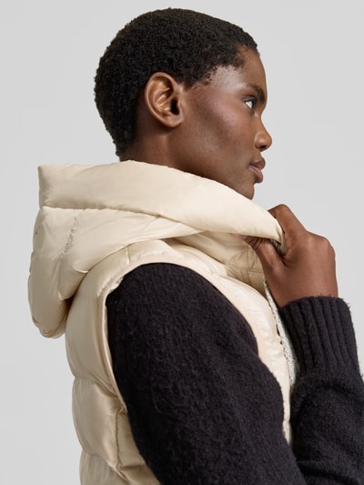 Vrouwenmodel draagt Regular Fit bodywarmer in stiksels van FUCHS SCHMITT met capuchon en Steekzakken, Nahaufnahme bovenlichaam. Ruglengte maat 36: 77 cm, Schouderbreedte: 41 cm, Borstwijdte: 51 cm.
