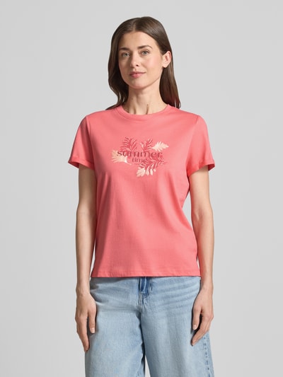 Frauenmodel trägt Regular Fit T-Shirt aus reiner Baumwolle von Tom Tailor in Optik: Unifarben mit Motiv-Print und Label-Print, Rundhals, Ärmelform: Kurzarm, Ärmelabschluss mit Umschlag, Materialverarbeitung: Jersey, Material: Reine Baumwolle, Farbe: Koralle, glatte Textur, Ganzkörperansicht von vorne.