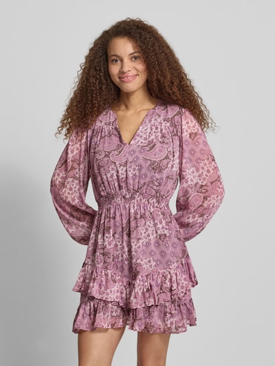 Frauenmodel trägt Minikleid mit Paisley-Muster im Stufen-Look von Review, lila-rosa Farbtöne, A-Linie, Ballonärmel, recyceltes Polyester, Ganzkörperansicht von vorne.